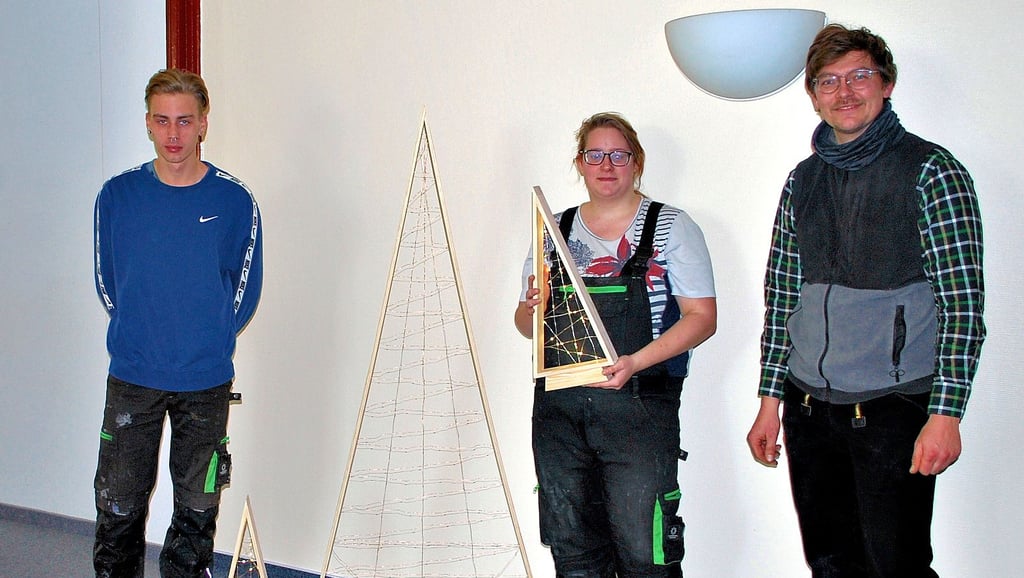 Mit von den Jugendlichen angefertigten Weihnachtsbäumen aus Holz bedankten sich Damian Arnsburg (von links), Lena Leißring und Werkstattpädagoge Fabian Spiegel beim Altmarkkreis.