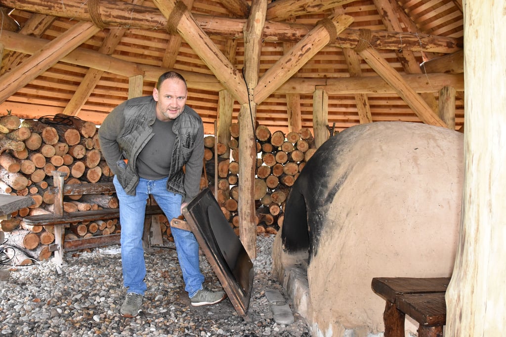 Wilko Florstedt vom Förderverein Randau, der das Steinzeitdorf trägt, steht am Backofen im Freilichtmuseum.