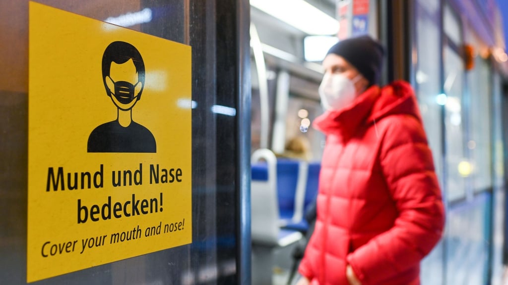 Eine Frau betritt mit FFP2-Maske eine Trambahn in München.