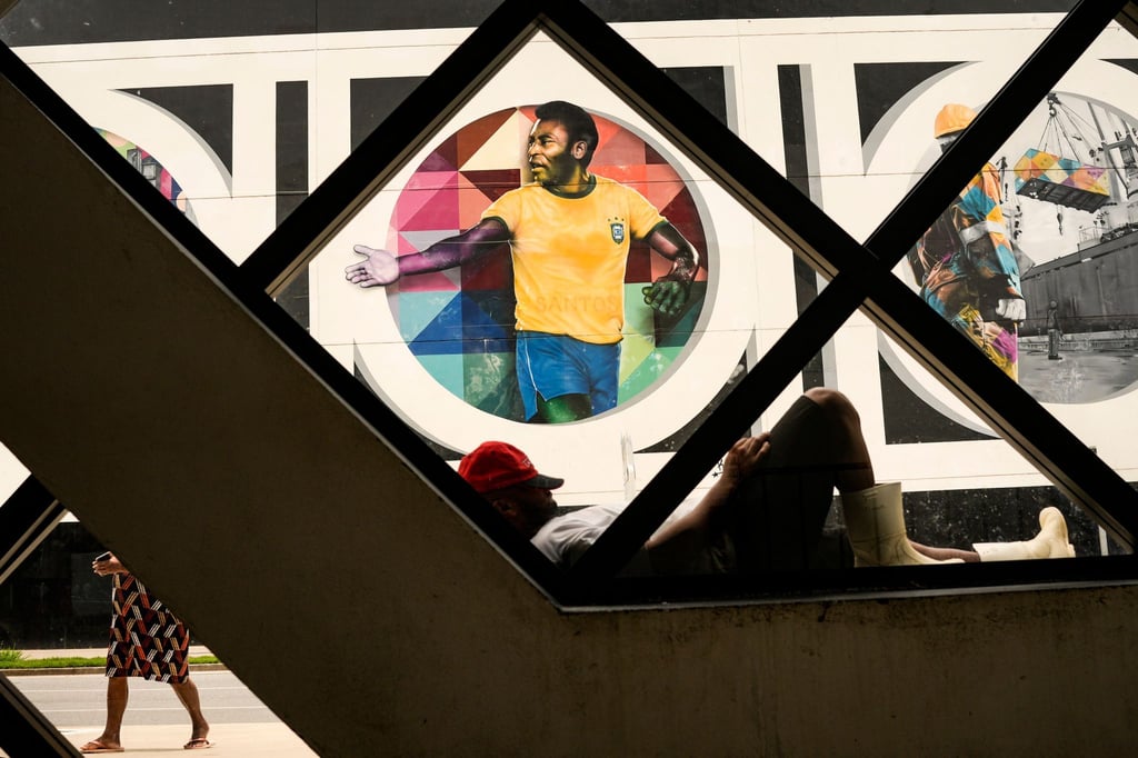 Ein Mann ruht sich vor einem Wandgemälde mit dem Bild der Fußballlegende Pele aus.