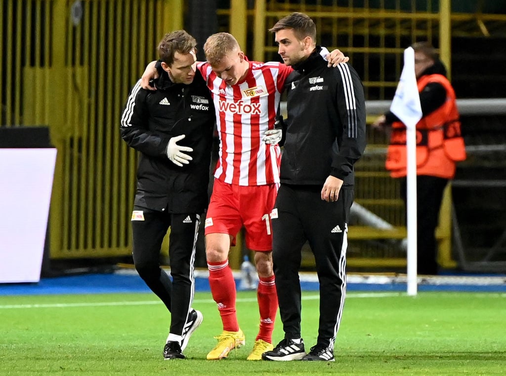 Maximilian Perschk (l), Leitender Physiotherapeut von Union Berlin, hilft dem verletzten Spieler Andras Schäfer (M) zusammen mit Marvin Minkus, dem Mannschaftsarzt, nach dem Abpfiff.