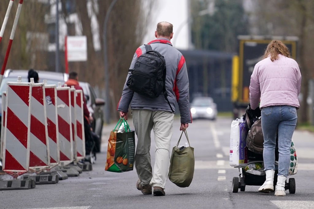 Ein geflüchteter Mann und eine Frau verlassen mit ihrem Gepäck die Flüchtlingsunterkunft.