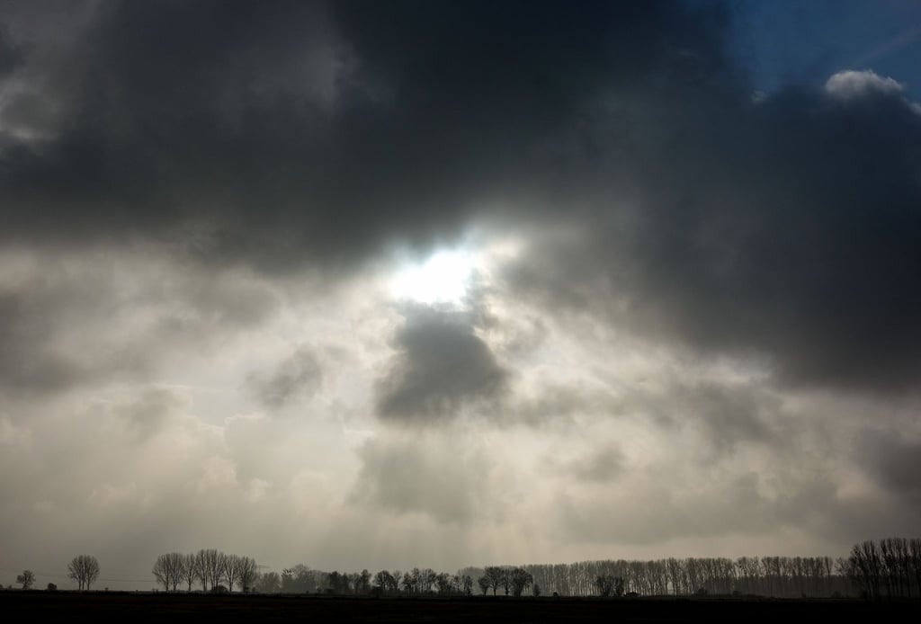 Die Sonne kommt nur kurzzeitig hinter einer dunklen Wolkendecke hervor.