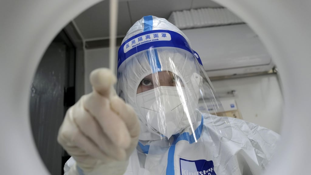 Ein medizinischer Mitarbeiter in Schutzkleidung während er einen PCR-Test zum Nachweis des Coronavirus durchführt.