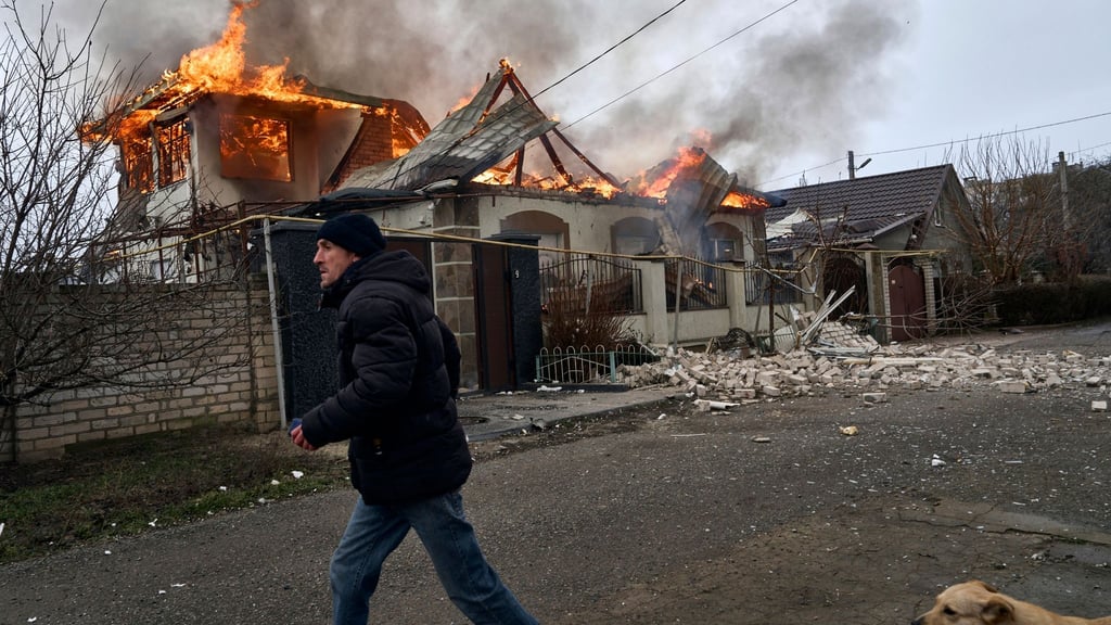Ein Anwohner läuft an einem brennenden Haus in Cherson vorbei, das nach ukrainischen Angaben bei russischem Beschuss am orthodoxen Weihnachtsabend getroffen wurde.