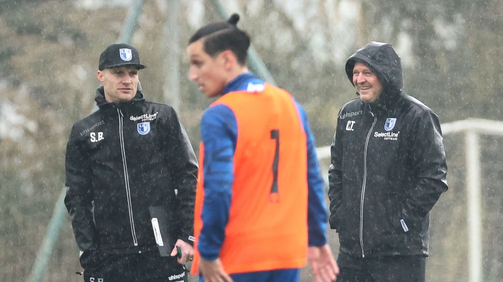 Erster Regentag in Side für den 1. FC Magdeburg. Silvio Bankert (l.) und Cheftrainer Christian Titz (r.) beobachten die Trainingseinheit von Vizekapitän Baris Atik und seinen Mannschaftskameraden.