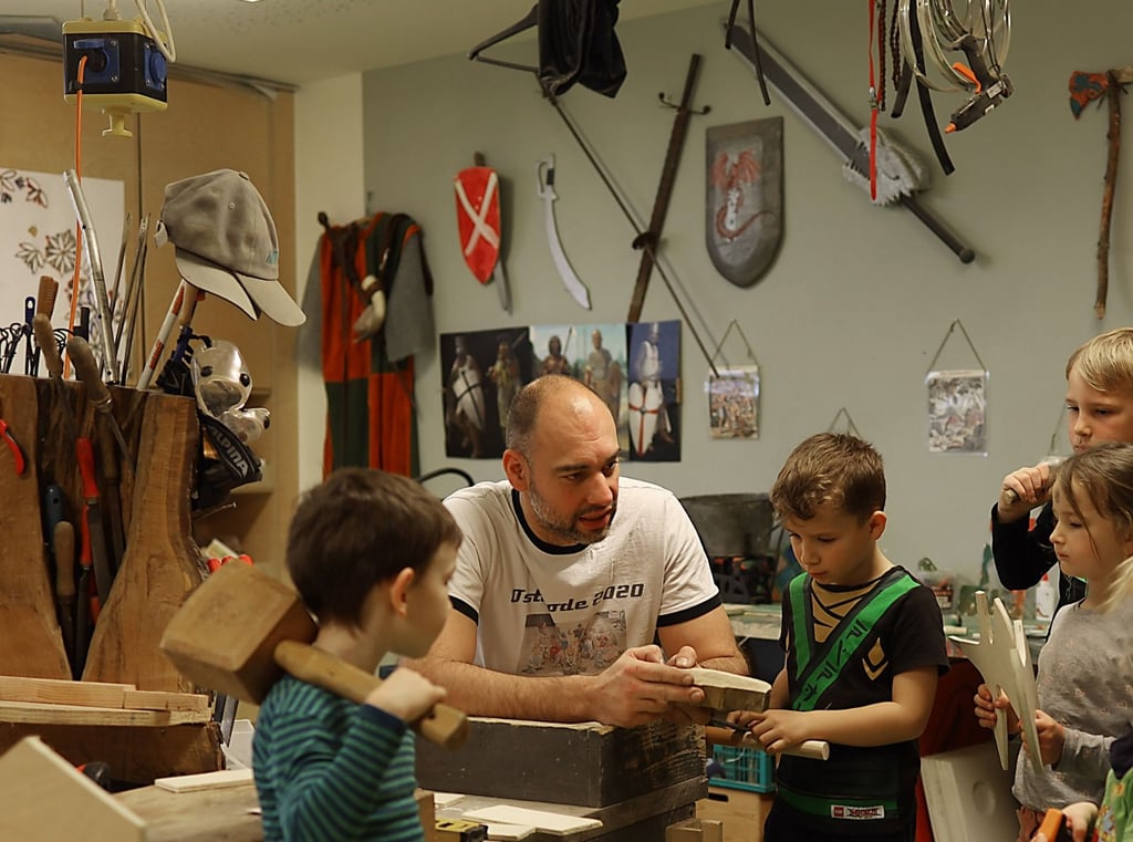 Erzieher Hannes Raschke erklärt den Kindern in der Werkstatt, wie sie etwas aus Holz gestalten können.