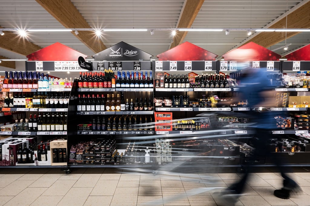Ein Mann geht mit seinem Einkaufswagen in einer Lidl-Filiale an Regalen mit Sansibar und Deluxe-Produkten vorbei.