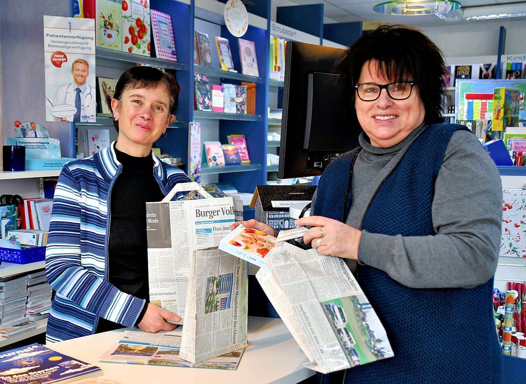 Christiane Feniuk und Marlies Hoffmann basteln Tragetaschen aus Zeitungspapier.