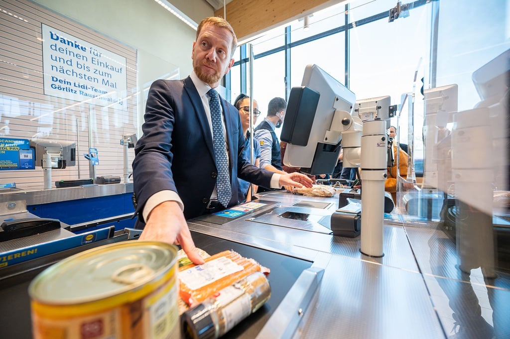 Michael Kretschmer (CDU), Ministerpräsident von Sachsen, zieht in Görlitz Lebensmittel über die Scannerkasse.