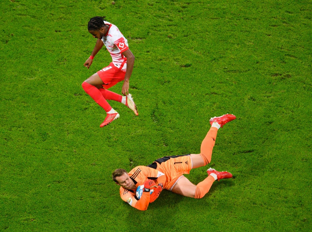 Leipzigs Christopher Nkunku (l) springt über Münchens Torwart Manuel Neuer.