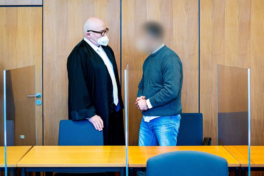 Der Angeklagte (r) steht neben seinem Verteidiger in einem Saal des Landgerichts.
