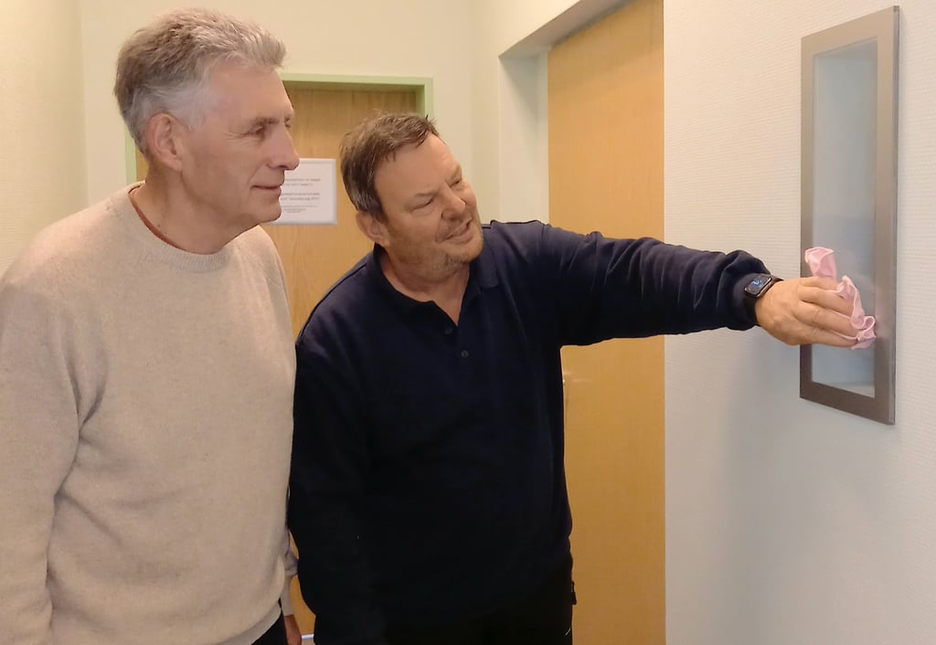 Joachim Kallmeyer (rechts) reibt im Beisein von Manfred Behrens das „Schaufensterchen“ vor der Zeitkapsel blank.