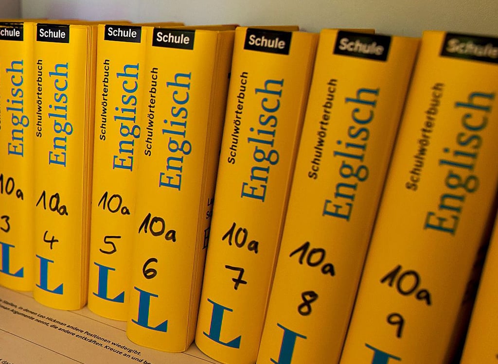 Ein Klassensatz Schulwörterbücher steht aufgereiht im Klassenzimmer. Wie sattelfest sind Behördenmitarbeiter in Englisch?