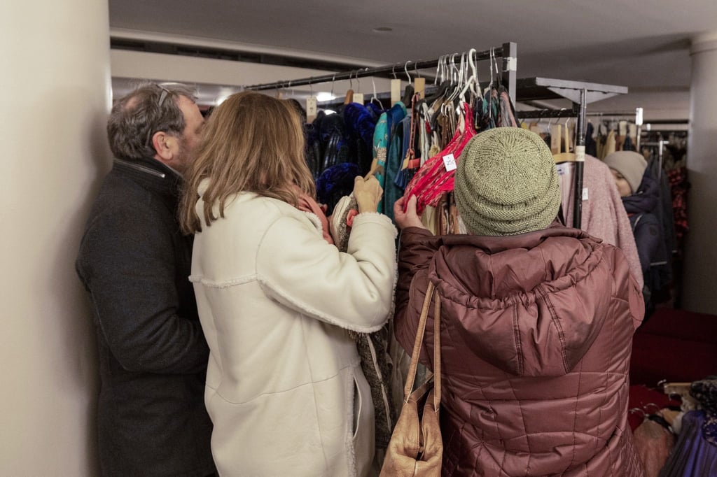 Ein Mann und zwei Frauen schauen sich im Foyer der Semperoper das Angebot beim Kostümverkauf an.