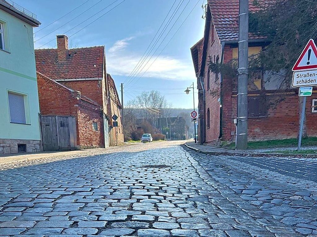 Die Hauptdurchgangsstraße in Huy-Neinstedt ist desolat – darauf wird mit Schildern (rechts) ausdrücklich hingewiesen. Obendrein hängen die Strom- und Telefonleitungen drei Jahrzehnte nach der Wende noch immer in der Luft. Voraussichtlich im Jahr 2024 soll die grundhafte Sanierung der Landesstraße beginnen.