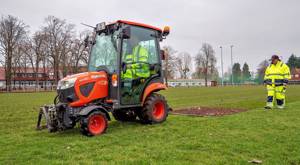 Bauhofmitarbeiter glätten Rasen auf dem Fußballfeld am Volkshaus