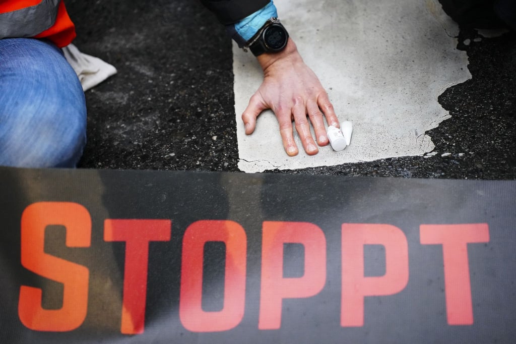 Klimaaktivistinnen und Klimaaktivisten der Organisation „Letzte Generation“ kleben für eine Blockade auf einer Straße.