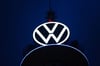 Das Volkswagen Logo leuchtet auf dem VW-Tower vor dunklem Himmel.