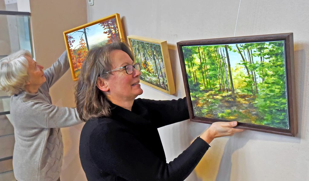 Heike Wolff hängt mit dem Malkreis Bilder für die neue Ausstellung in der Bibliothek auf.