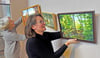 Heike Wolff hängt mit dem Malkreis Bilder für die neue Ausstellung in der Bibliothek auf. 
