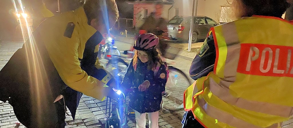 Polizeibeamtin Simone Deseife erklärt einem Mädchen vor der Max-Lingner-Schule, wie die Fahrradbeleuchtung in Gang zu setzen ist.