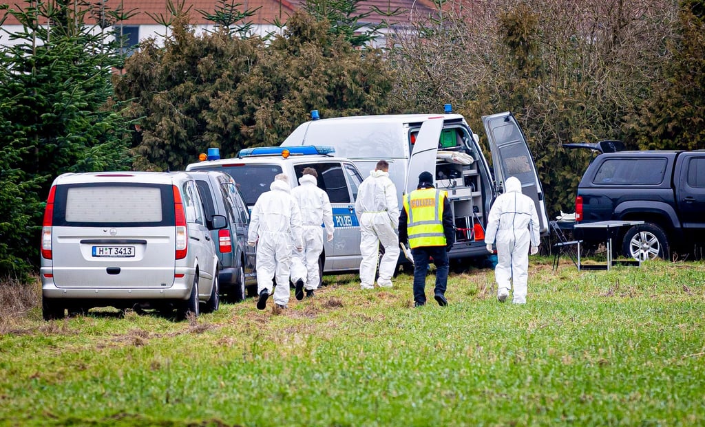 Mitarbeiter der Spurensicherung der Polizei gehen über eine Wiese.