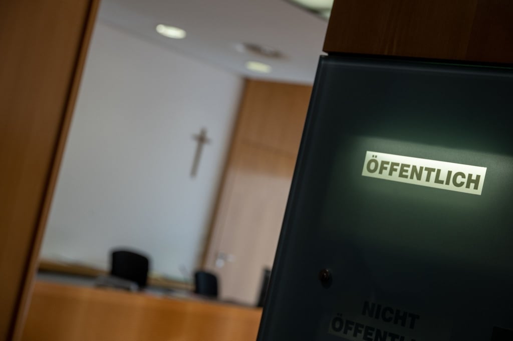 Eine Anzeigetafel weist an einem Sitzungssal auf eine öffentliche Verhandlung hin.
