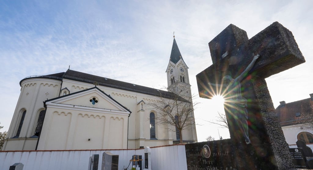 Das Kreuz eines Grabsteins steht vor der katholische Kirche St. Nikolaus in Garching.