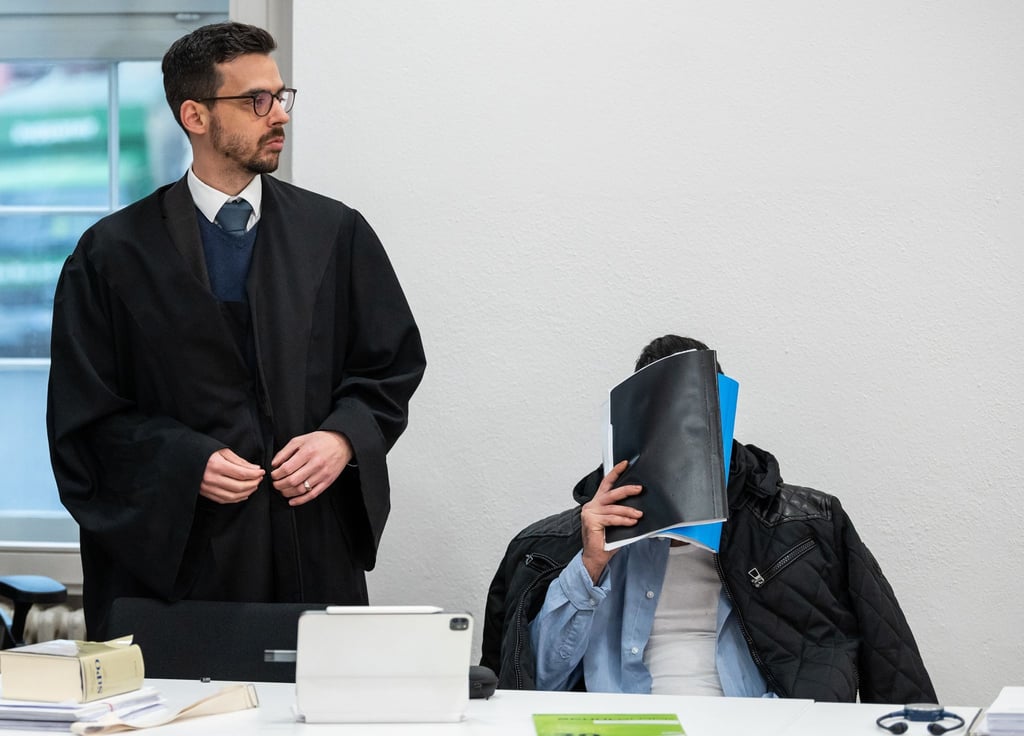 Der Mann, der wegen Vergewaltigung und Freiheitsberaubung an seiner Schwester angeklagt ist, verdeckt vor Beginn des Prozesses sein Gesicht, neben ihm sein Verteidiger (l).