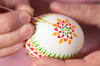 Mit einem selbst gefertigten Feder-Pinsel wird farbiges heißes Wachs auf das Ei aufgetragen.