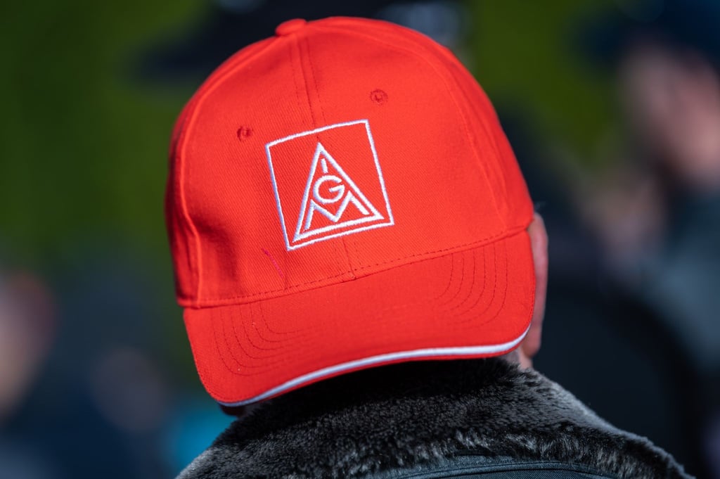 Ein Teilnehmer einer Kundgebung der Gewerkschaft IG Metall trägt während eines Warnstreiks eine Mütze mit dem Logo der IG Metall.