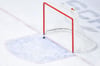 Ein Puck fliegt in ein leeres Eishockey-Tor.