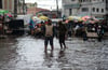 Menschen waten durch das Hochwasser einer überfluteten Straße in Antananarivo.