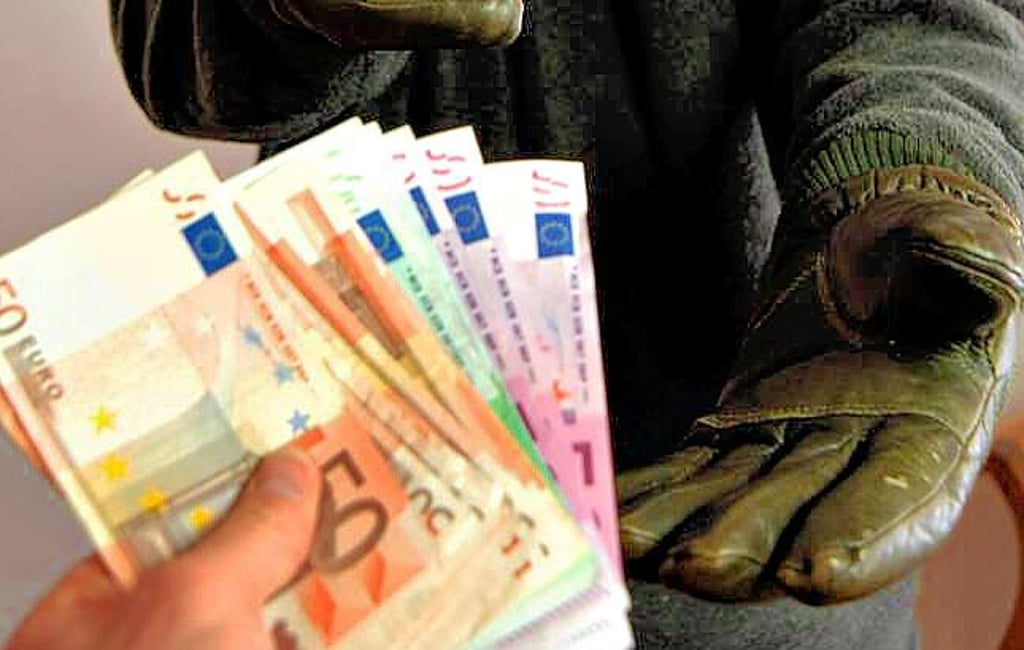 Ein dunkel gekleideter Räuber fordert Bargeld.