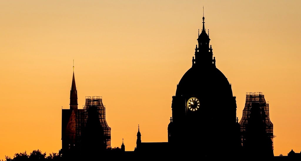 Die Silhouette der Kuppel vom Neuen Rathaus und dem Turm der Marktkirche vor dem Abendhimmel.