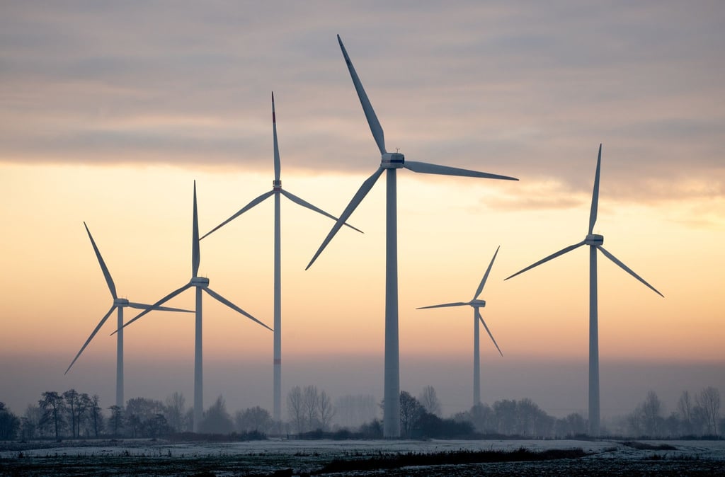 Windkraftanlagen stehen bei winterlichem Wetter vor dem Abendhimmel.