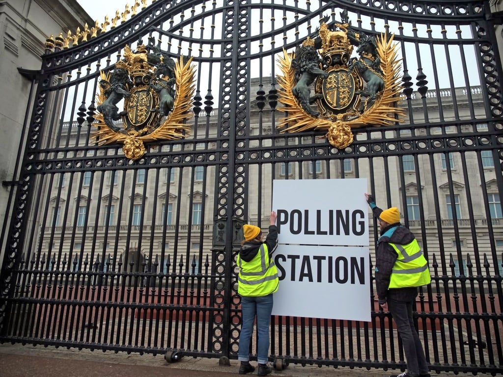 Anhänger der Kampagnengruppe Republic hängen ein Wahllokalschild ans Geländer des Buckingham Palace in London.