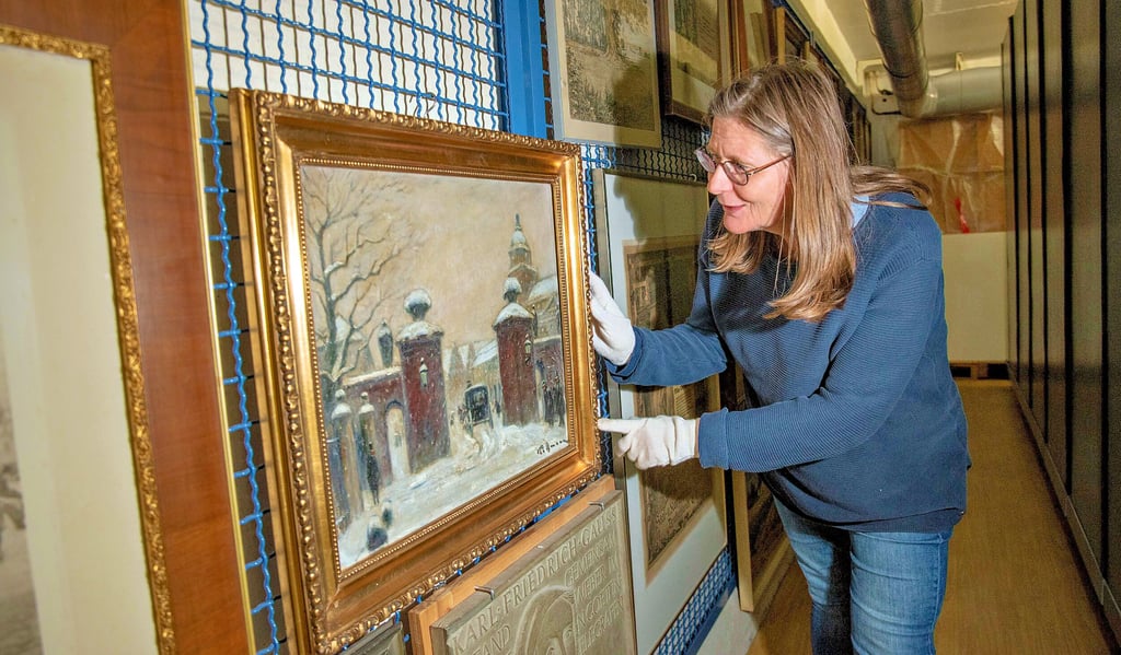 Karin Weigt vom Museum für Stadtgeschichte zeigt im Depot des Museums ein Wintergemälde von Kurt Pallmann.