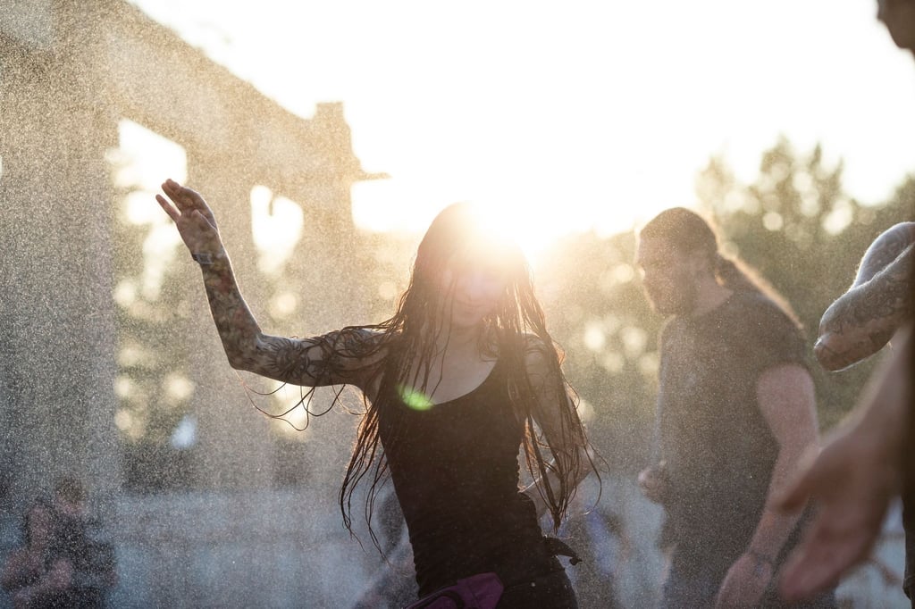 Eine Besucherin tanzt im Sonnenuntergang im Wassernebel auf dem Full Force Festival in Ferropolis.
