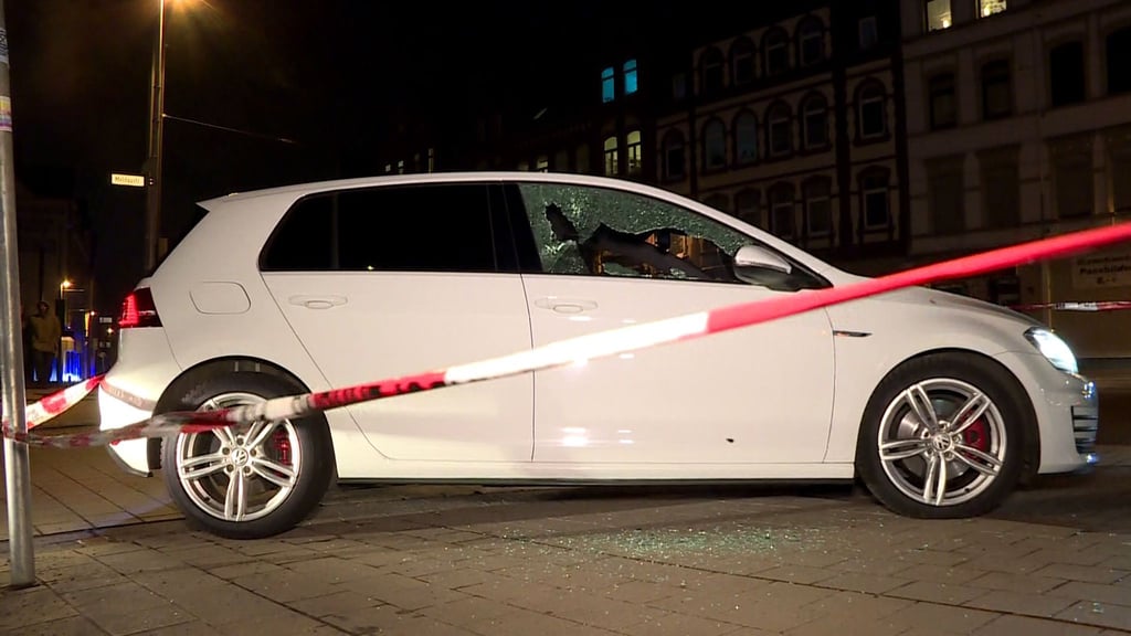 Absperrband hängt um ein Auto mit einem zerstörten Seitenfenster.