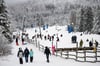 Wintersportler gehen mit ihren Schlitten an einem Rodellift im Harz entlang. In Niedersachsen ist der letzte Tag der Zeugnisferien.