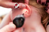 Mit einem Otoskop untersucht eine Kinderärztin ein Ohr eines Mädchens im Rahmen einer U9-Untersuchung.