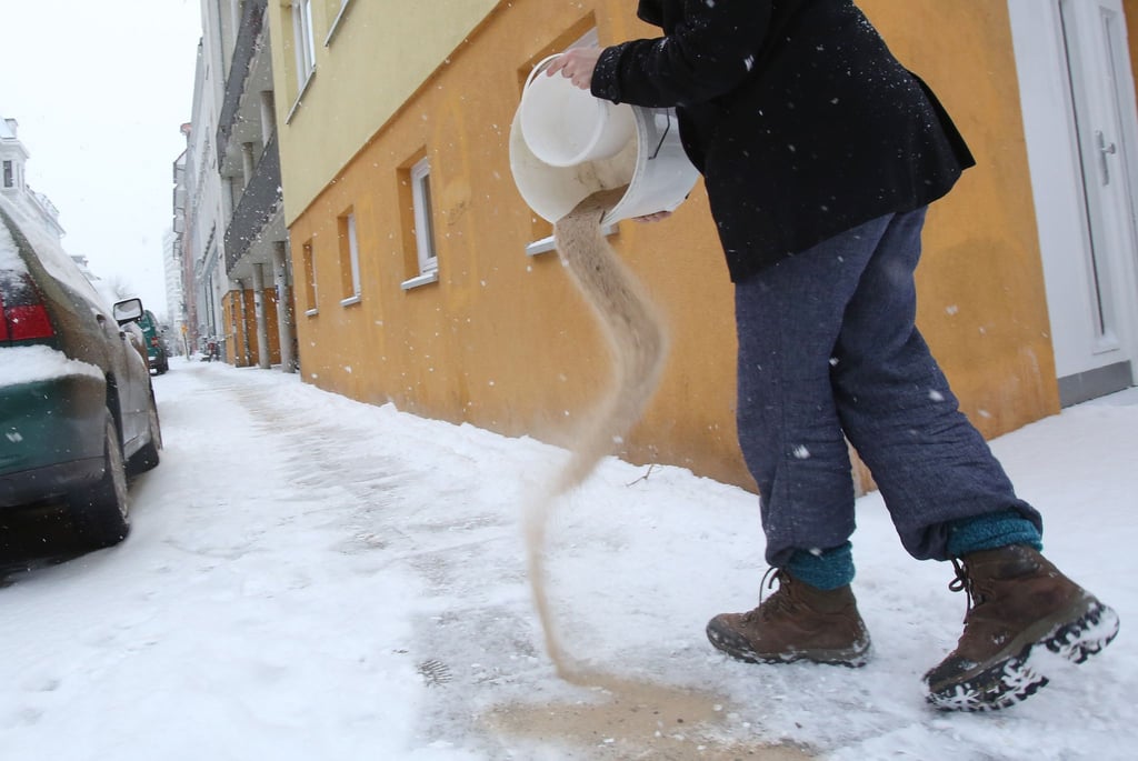 Sand lässt zwar nicht den Schnee und das Eis tauen, aber es stumpft sie ab - und damit rutscht man darauf nicht mehr aus.