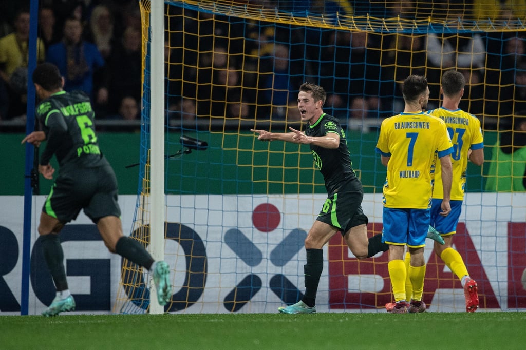 Der Wolfsburger Jakub Kaminski (M.) feiertseinen Siegtreffer.