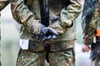 Bundeswehrsoldaten stehen mit überkreuzten Händen zusammen.