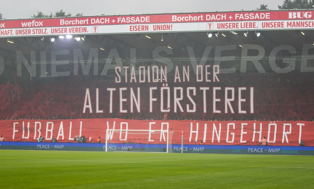 Schriftzug vor Tribüne zeigt: Stadion An der Alten Försterei. Fußball, wo er hingehört.