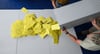 Stimmzettelumschläge für eine Briefwahl werden aus einer Wahlurne geschüttet.
