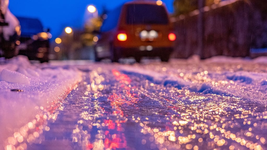 Eine dünne Eisschicht überzieht am frühen Morgen eine Straße.