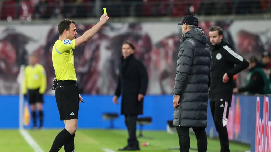 Referee Felix Zwayer zeigt Trainer Marco Rose (RB Leipzig) die gelbe Karte.